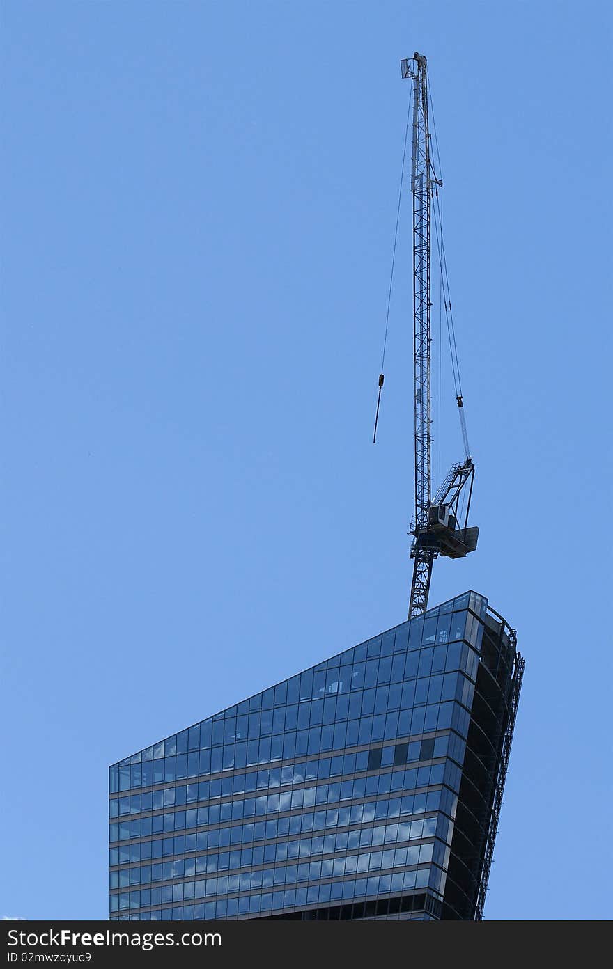 Construction crane at the windows of a skyscraper backdrop of glass and concrete