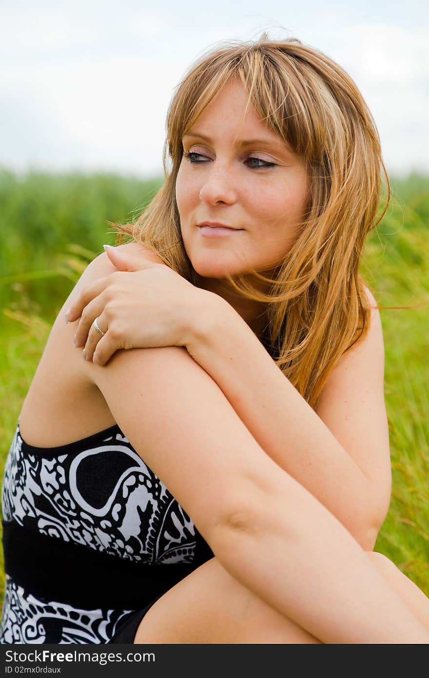 Woman in green meadow sitting enjoying spring autumn time. Woman in green meadow sitting enjoying spring autumn time