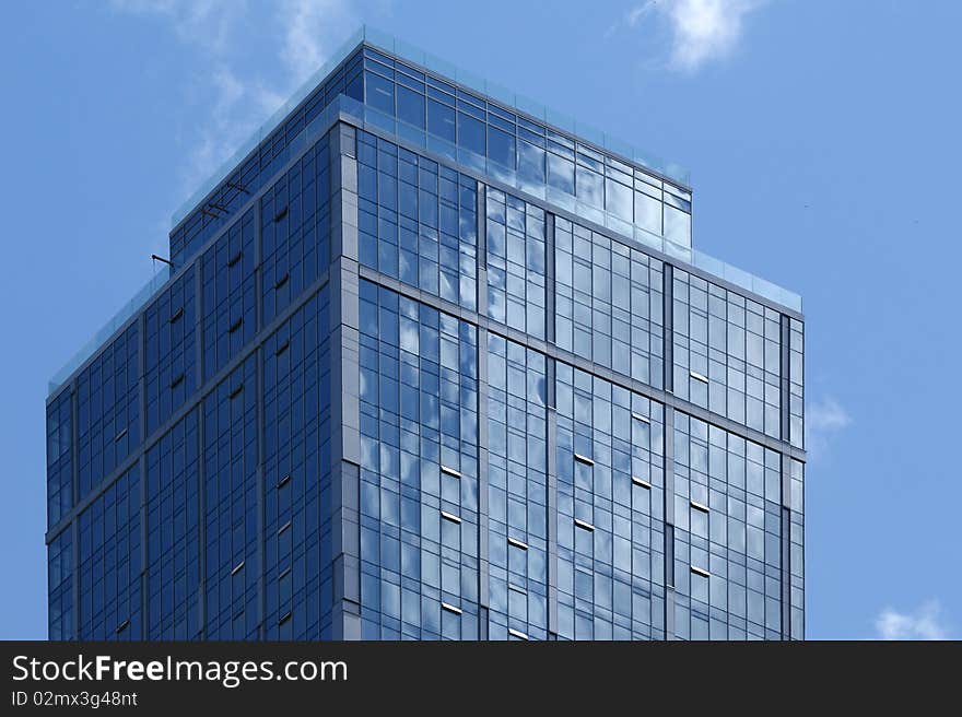 Reflection of a cloudy sky in glass wall of an office building