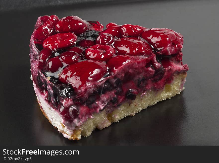 Small berries tart piece macro shot over black background