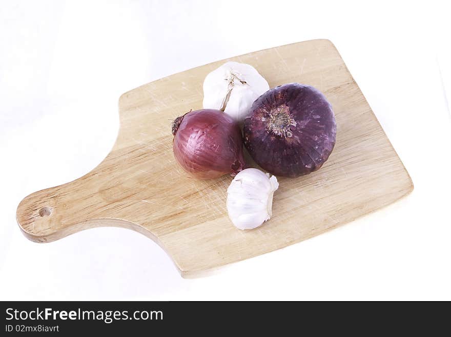 A selection of vegetables of root foods on a cutting board ready for cutting isolated on a white background. A selection of vegetables of root foods on a cutting board ready for cutting isolated on a white background