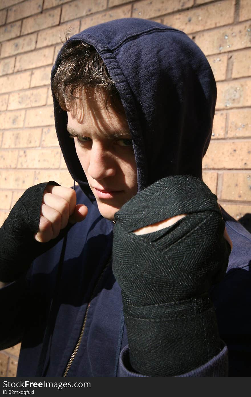 Portrait of young male boxer training outdoors.