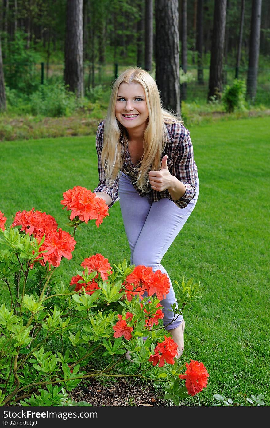 Beautiful gardener woman with red flower bush outdoors