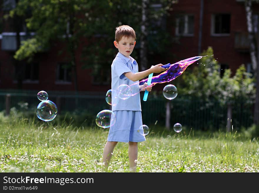 Boy is played with soap bubbles in the street