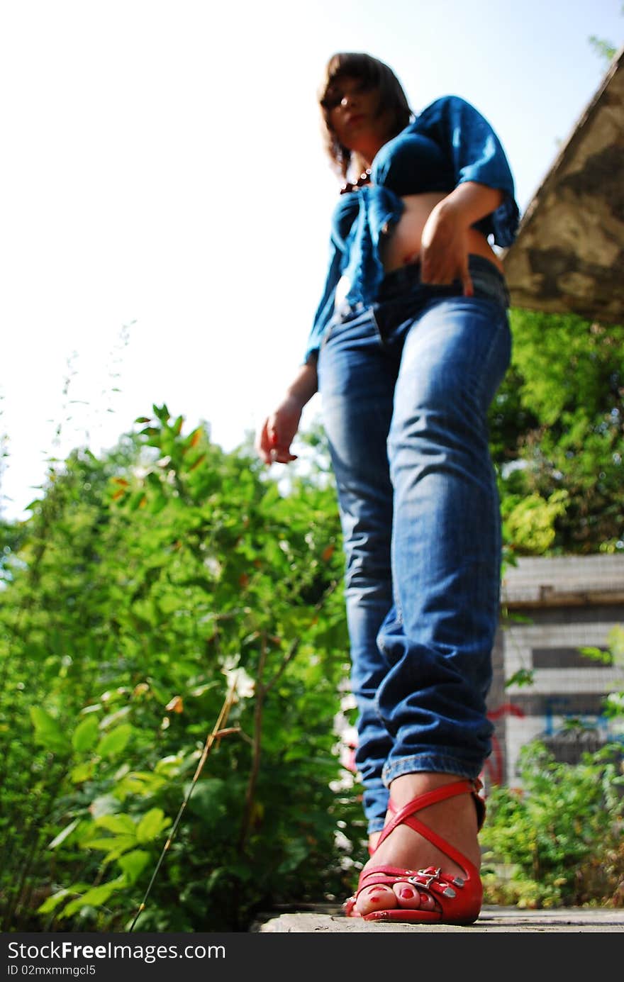 The young woman against the nature. Red barefoot persons. Jeans