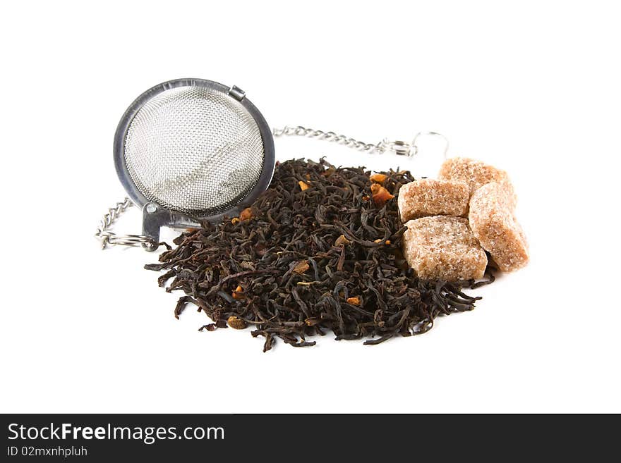 Metallic tea-stainer with a heap of dry tea leaves and four pieces of brown sugar isolated on white. Metallic tea-stainer with a heap of dry tea leaves and four pieces of brown sugar isolated on white