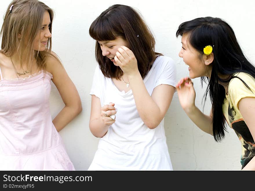 Three female friends standing in front of a white wall