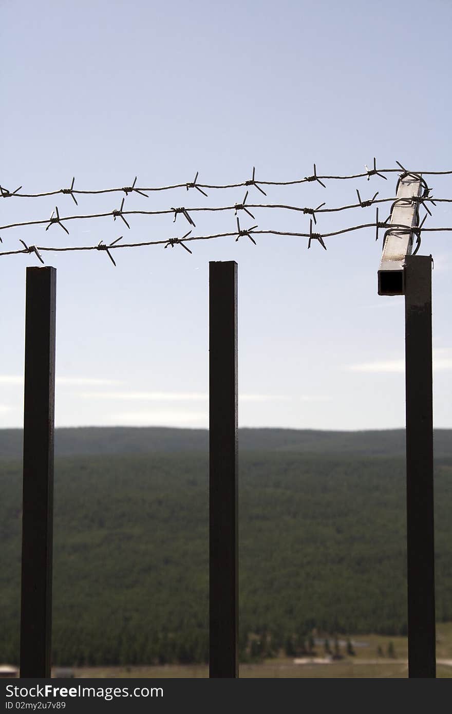 Fence with a barbed wire on a background of blue sky