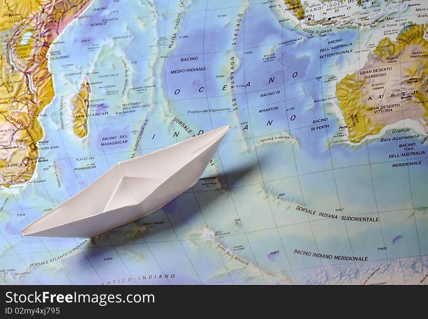 A white toy paperboat on a map. A white toy paperboat on a map.