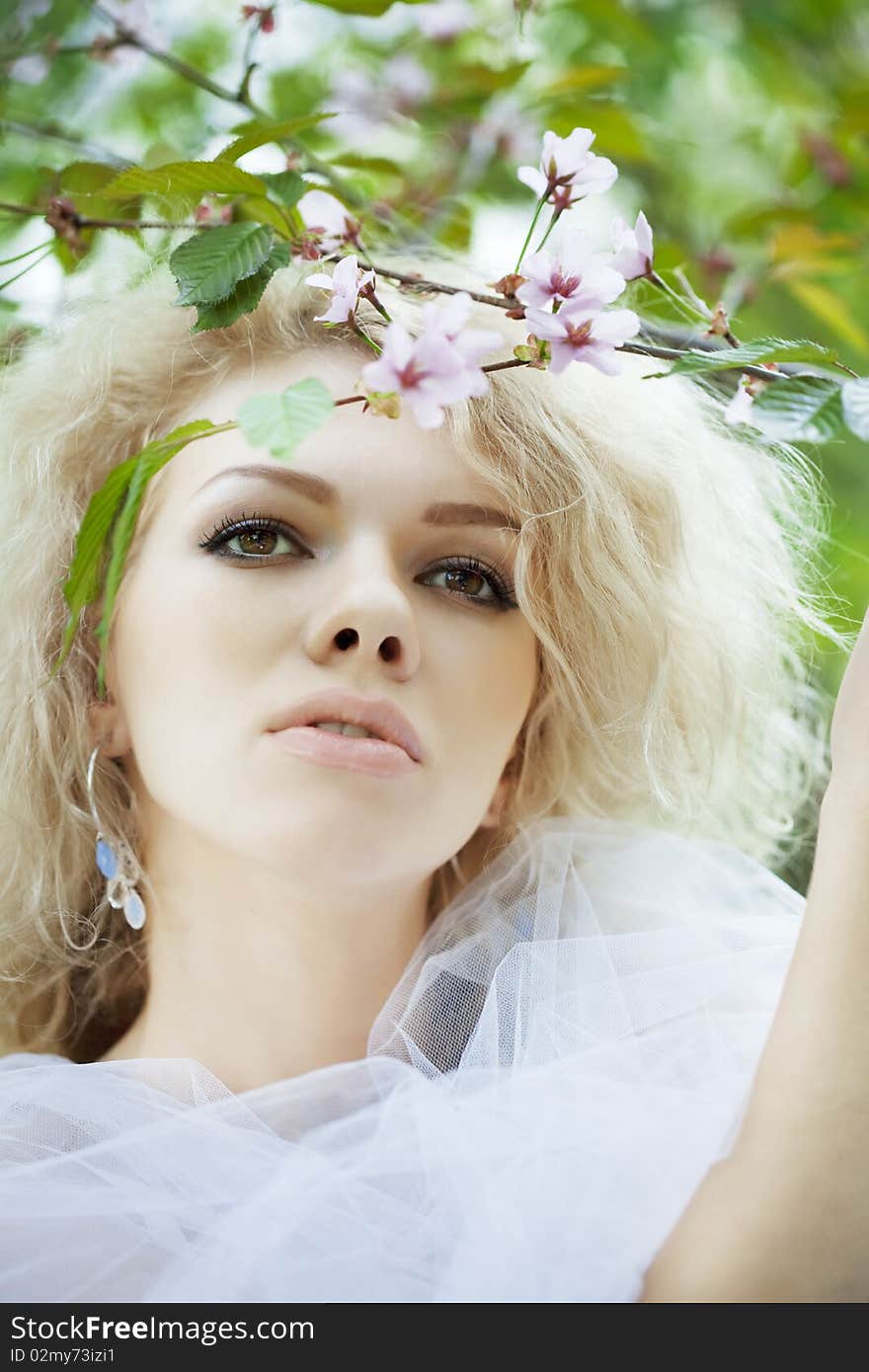 The image of a beautiful positive girl in a park, surrounded by flowers