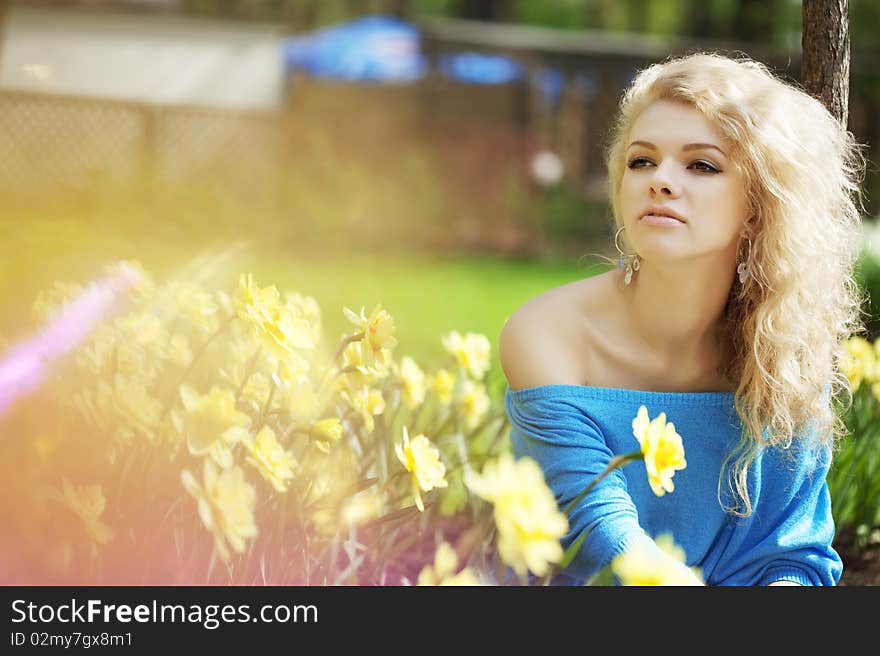 The image of a beautiful positive girl in a park, surrounded by flowers