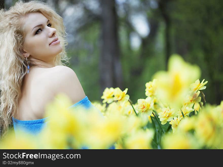 The image of a beautiful positive girl in a park, surrounded by flowers