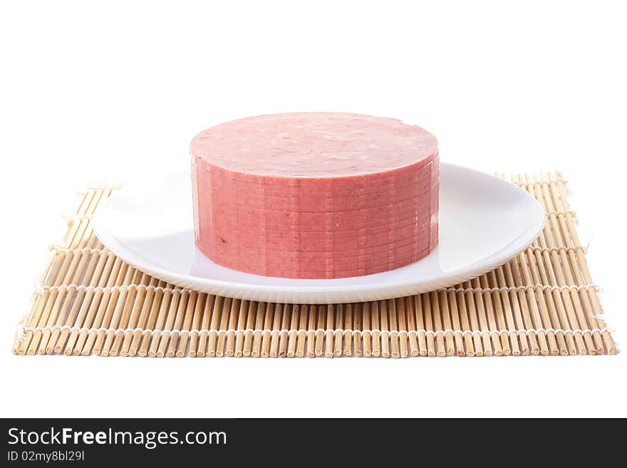 Sausage with fat impregnations is cut by slices and placed on a white plate. Sausage with fat impregnations is cut by slices and placed on a white plate.