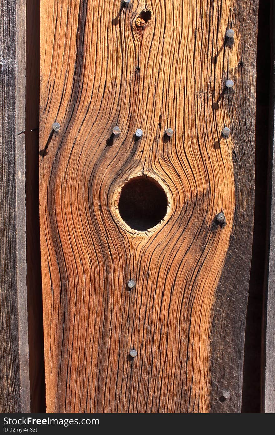 View of a knot hole in a weathered board on the side of building. View of a knot hole in a weathered board on the side of building.