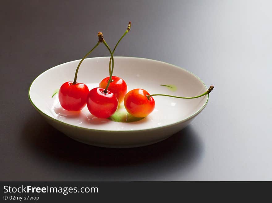 Four red fresh yummy cherry on a dish.