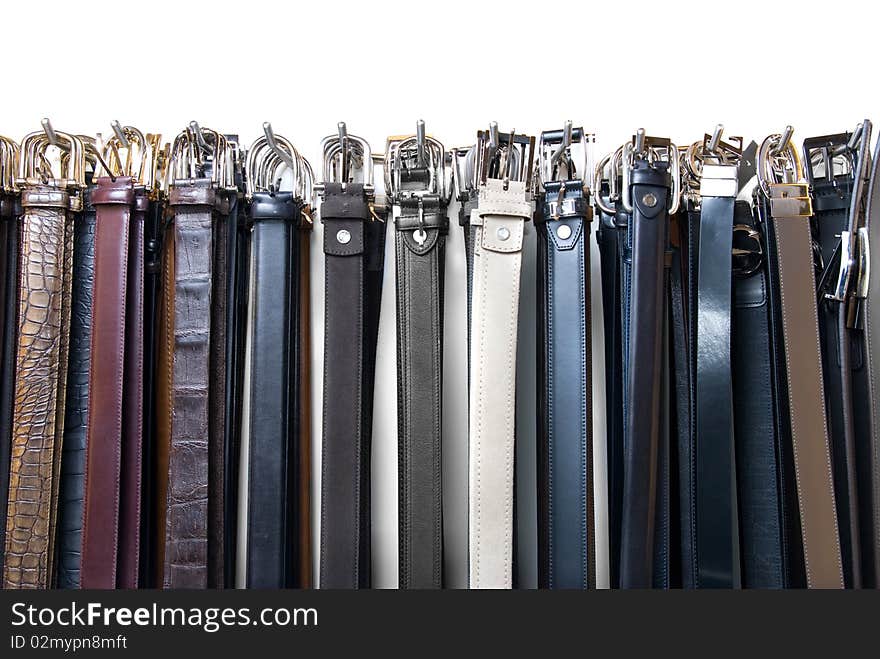 A lot of leather belts in store isolated on white