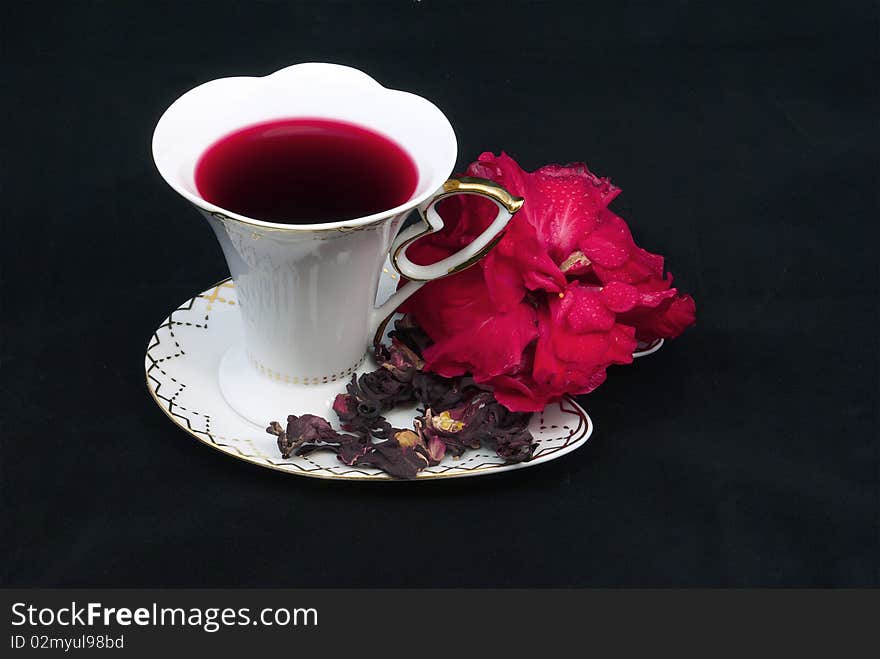 Tea of karkade in a white porcelain cup on a black background. Tea of karkade in a white porcelain cup on a black background