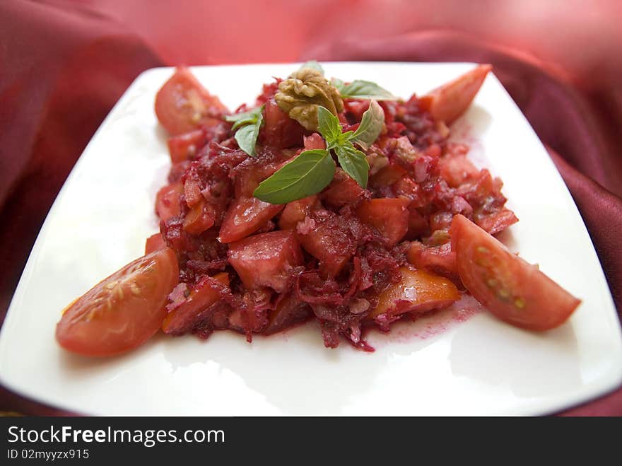 Bright red salad with fresh raw tomatoes, beets, walnuts, basil and lemon juice