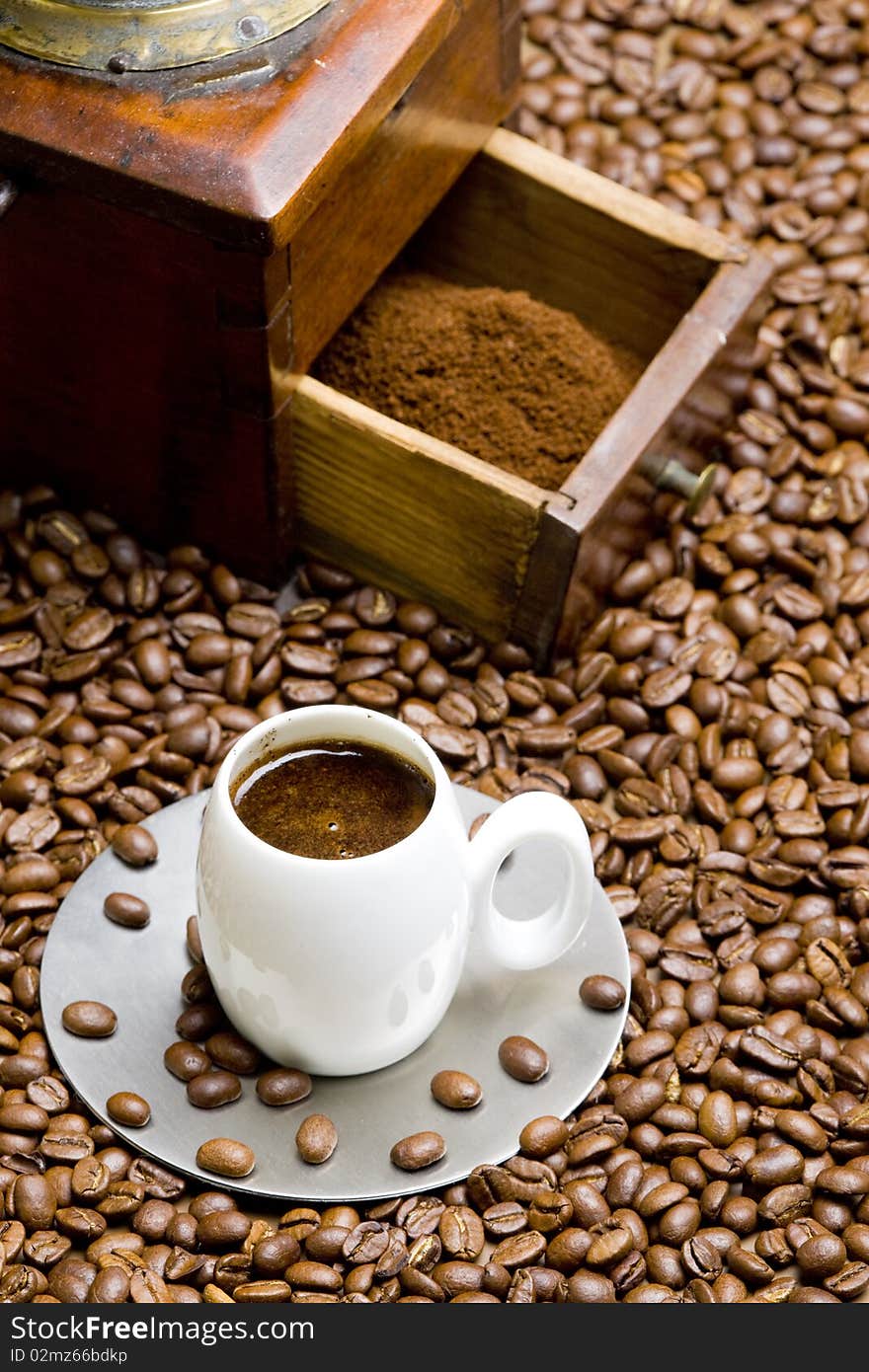 Detail of coffee mill with coffee beans and cup of coffee