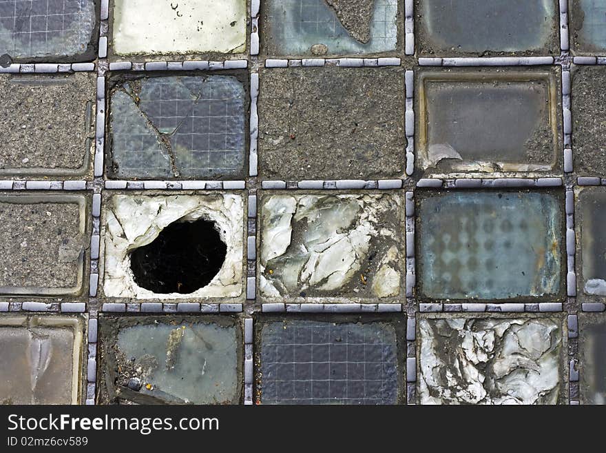 An old neglected glass inset on a city pavement. An old neglected glass inset on a city pavement