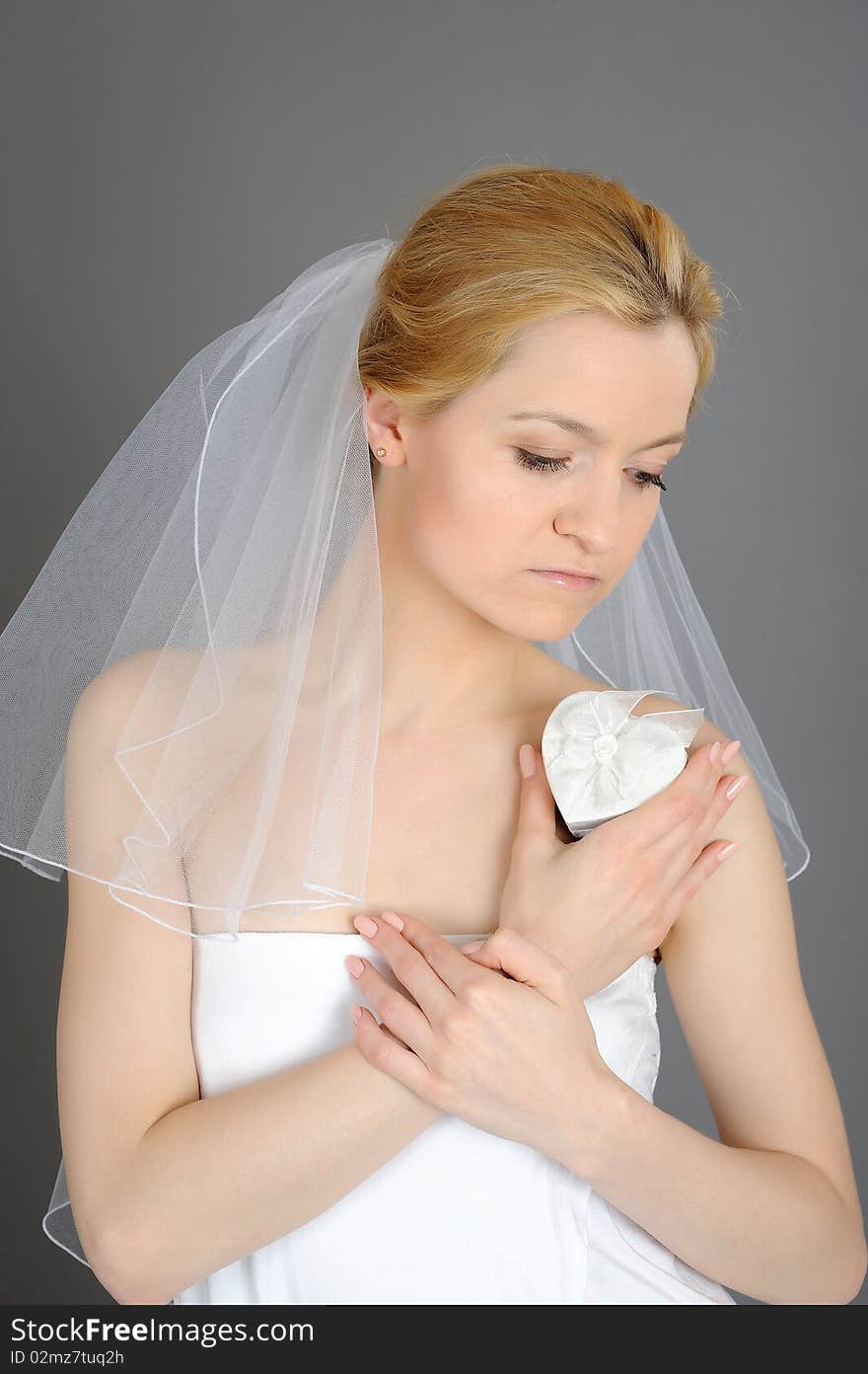 Beautiful young bride in white veil with present