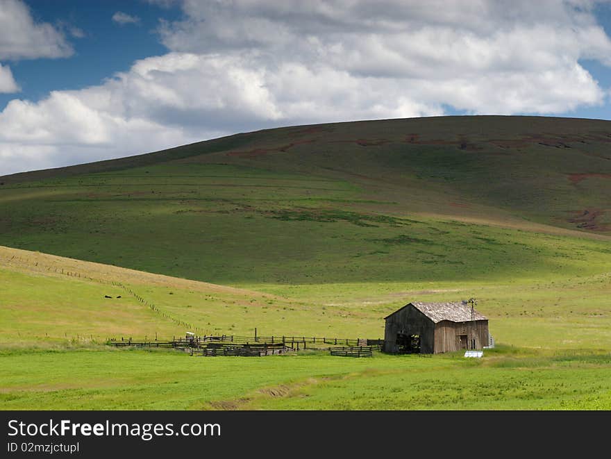 Shadows from an approaching cloud sweep down a hill toward a barn in the eastern Oregon desert. Shadows from an approaching cloud sweep down a hill toward a barn in the eastern Oregon desert