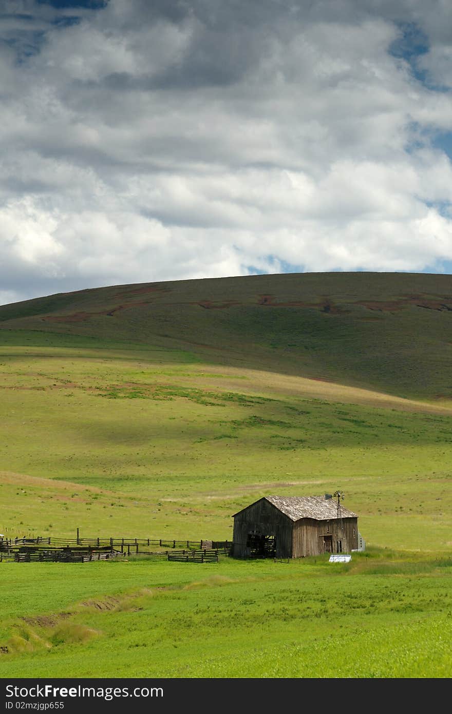 Shadows from an approaching cloud sweep down a hill toward a barn in the eastern Oregon desert. Shadows from an approaching cloud sweep down a hill toward a barn in the eastern Oregon desert