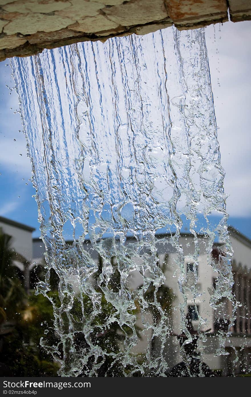 Fountain water falling down with the cloudy sky in the background