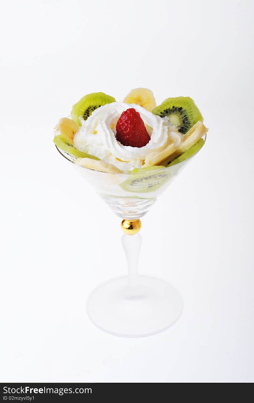 Fresh chopped strawberries, kiwi and banana with whipped cream in glasswares. Fresh chopped strawberries, kiwi and banana with whipped cream in glasswares