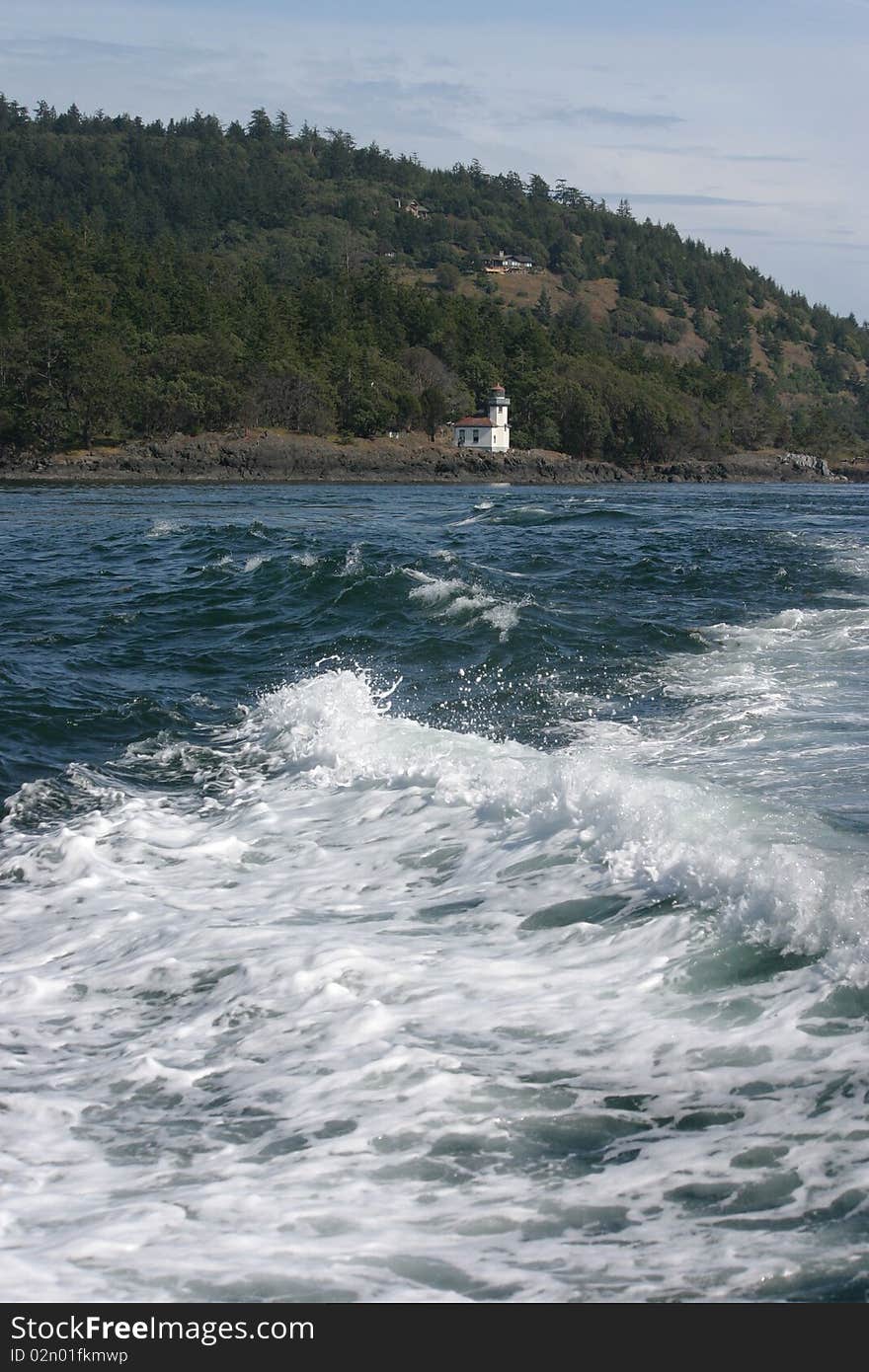 The wake of a boat causes white foam while looking back at the Lime Kiln Lighthouse on the San Juan Islands in Washington state. The wake of a boat causes white foam while looking back at the Lime Kiln Lighthouse on the San Juan Islands in Washington state.