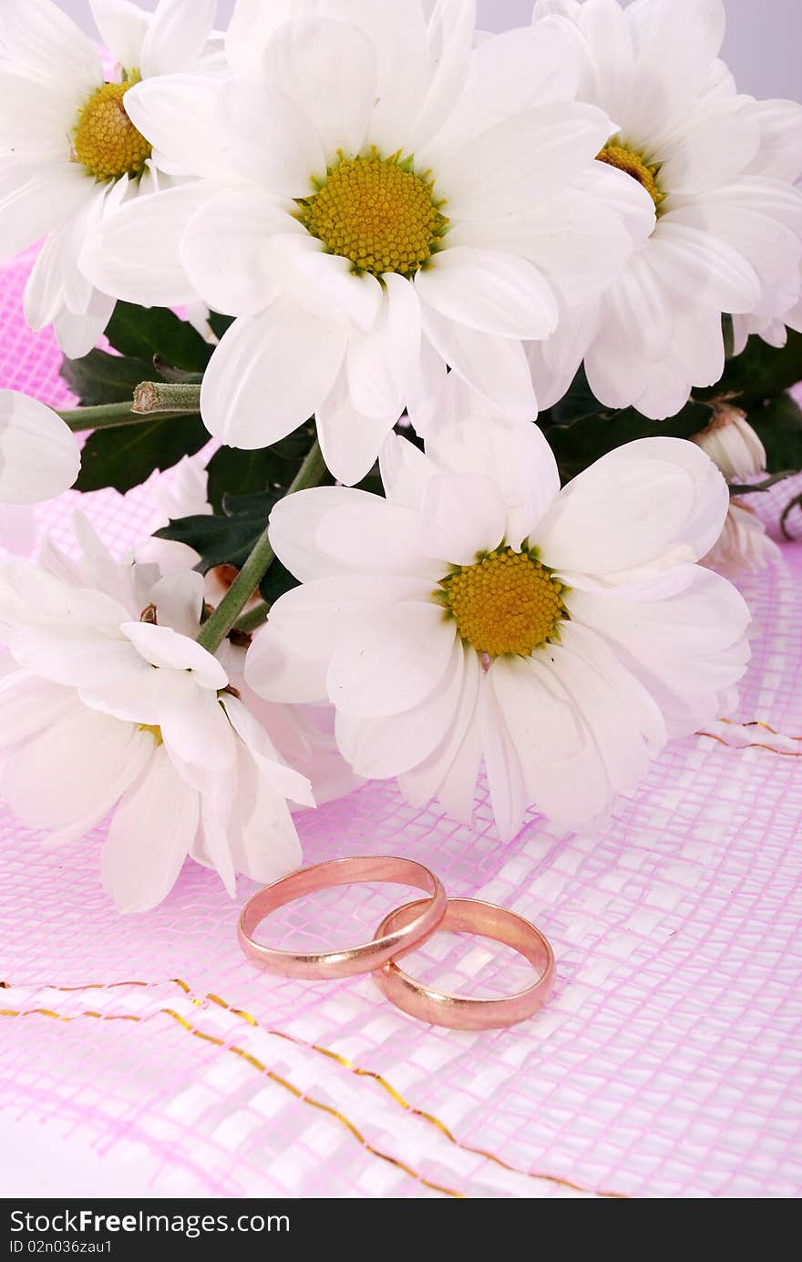 Wedding rings and flowers composition. White petals.