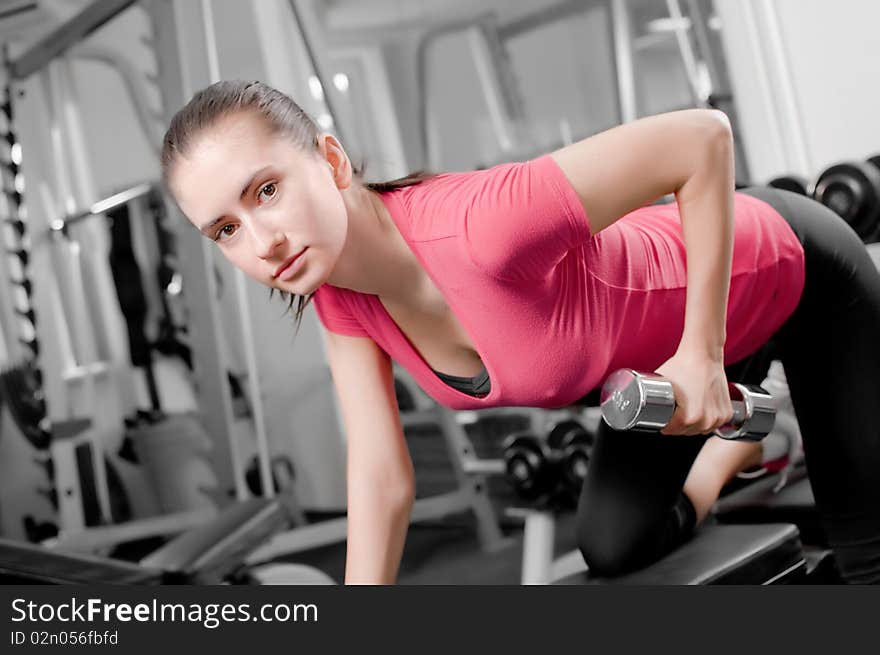 Pretty young woman training with dumbbells in a gym