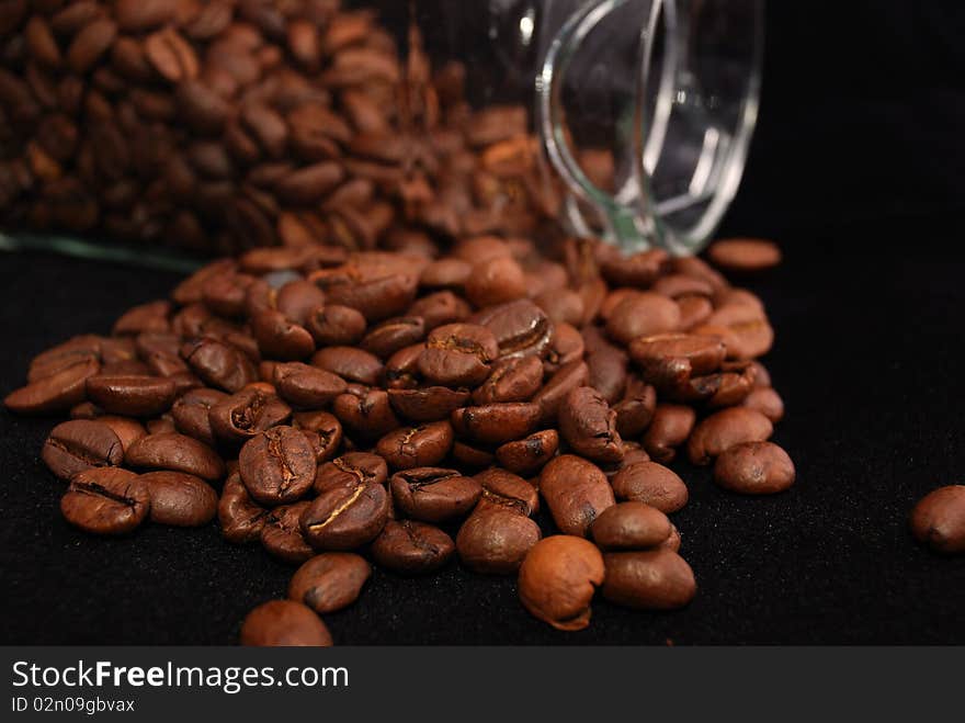 Brown fried grains of coffee scattered on a black background