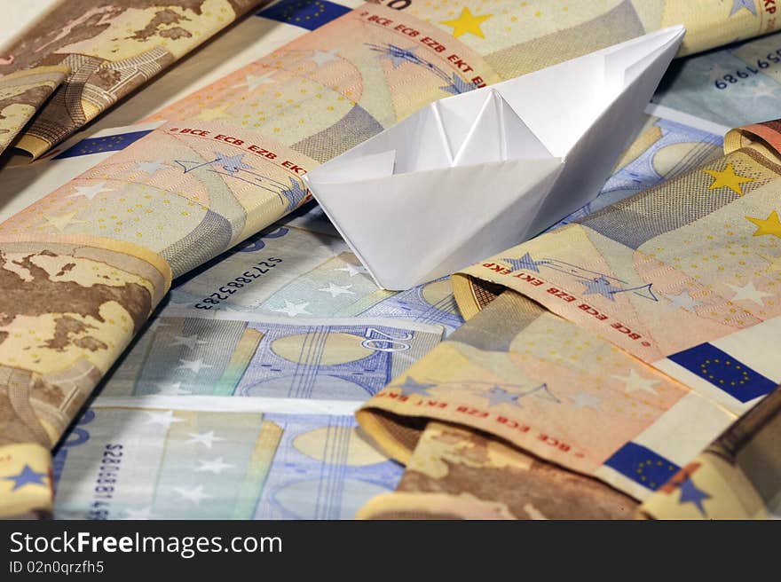 A white toy paperboat on a flow of cash. A white toy paperboat on a flow of cash.