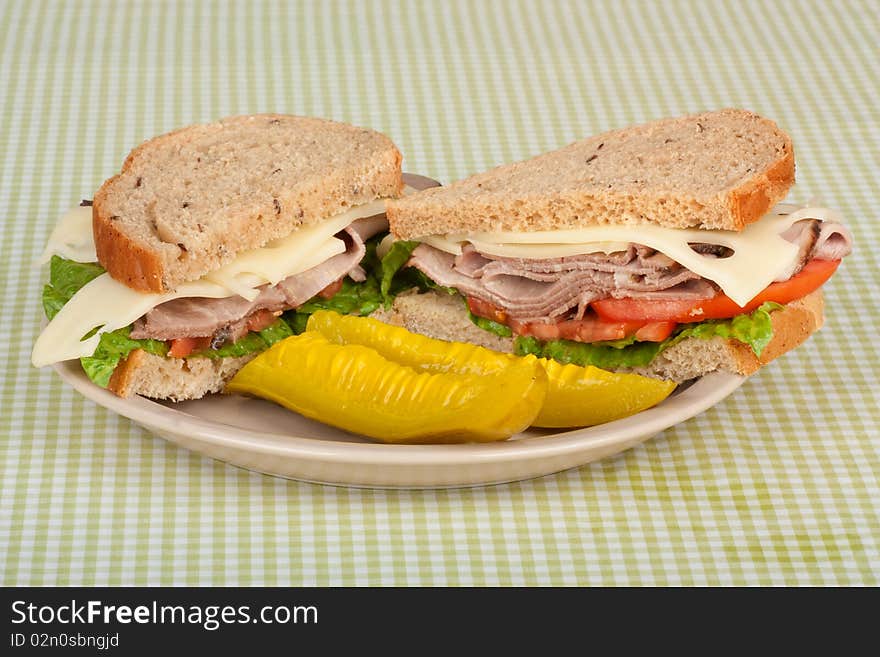 Roast beef sandwich on rye bread with swiss cheese, tomato, lettuce and pickles