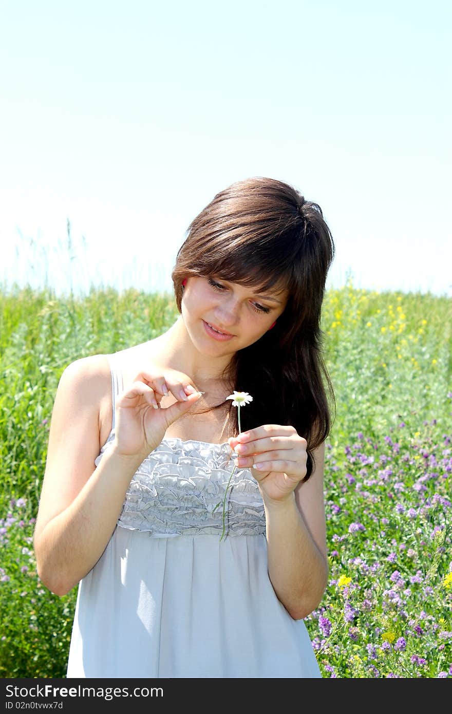 The young girl guesses on a camomile flower