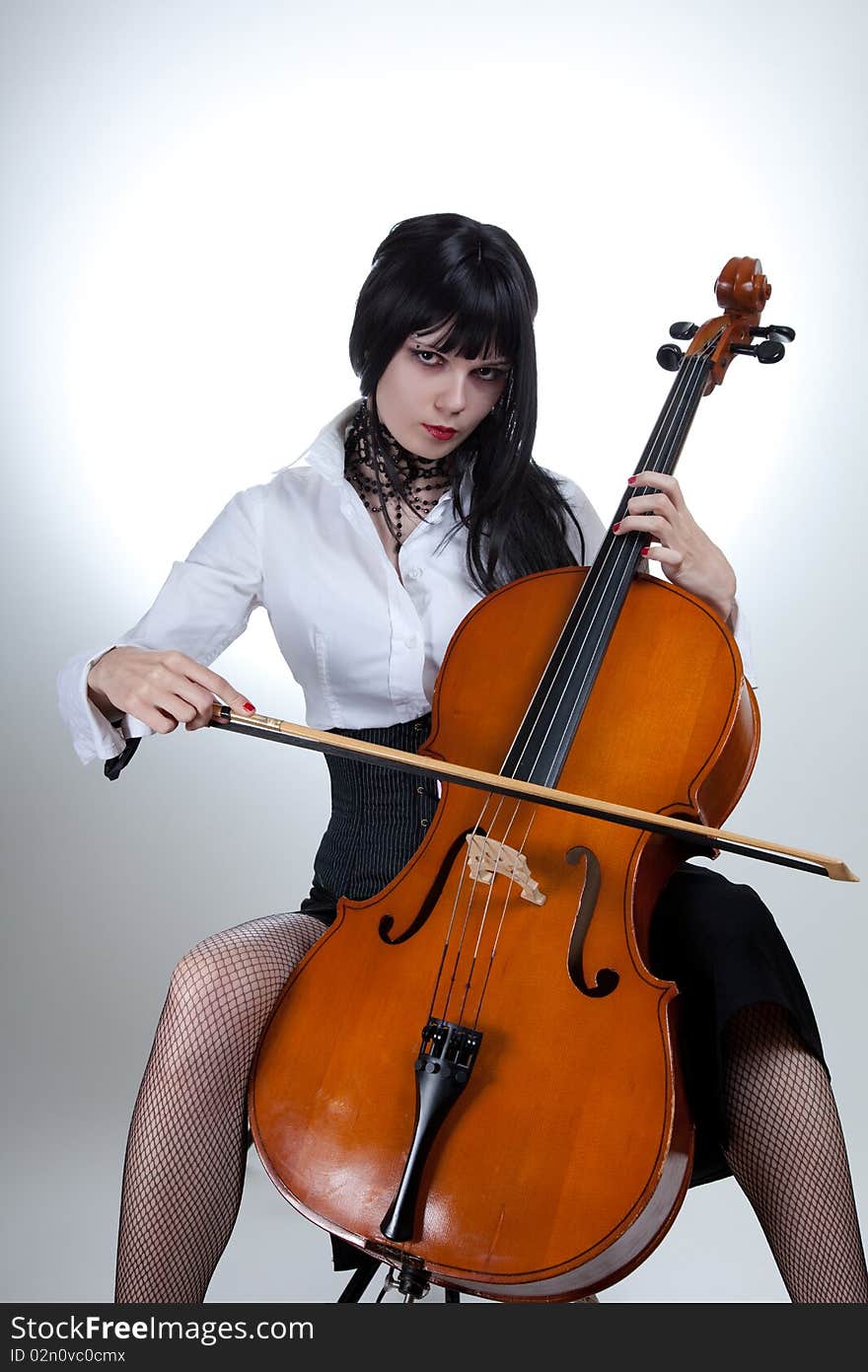 Young woman playing cello, studio shot over white background