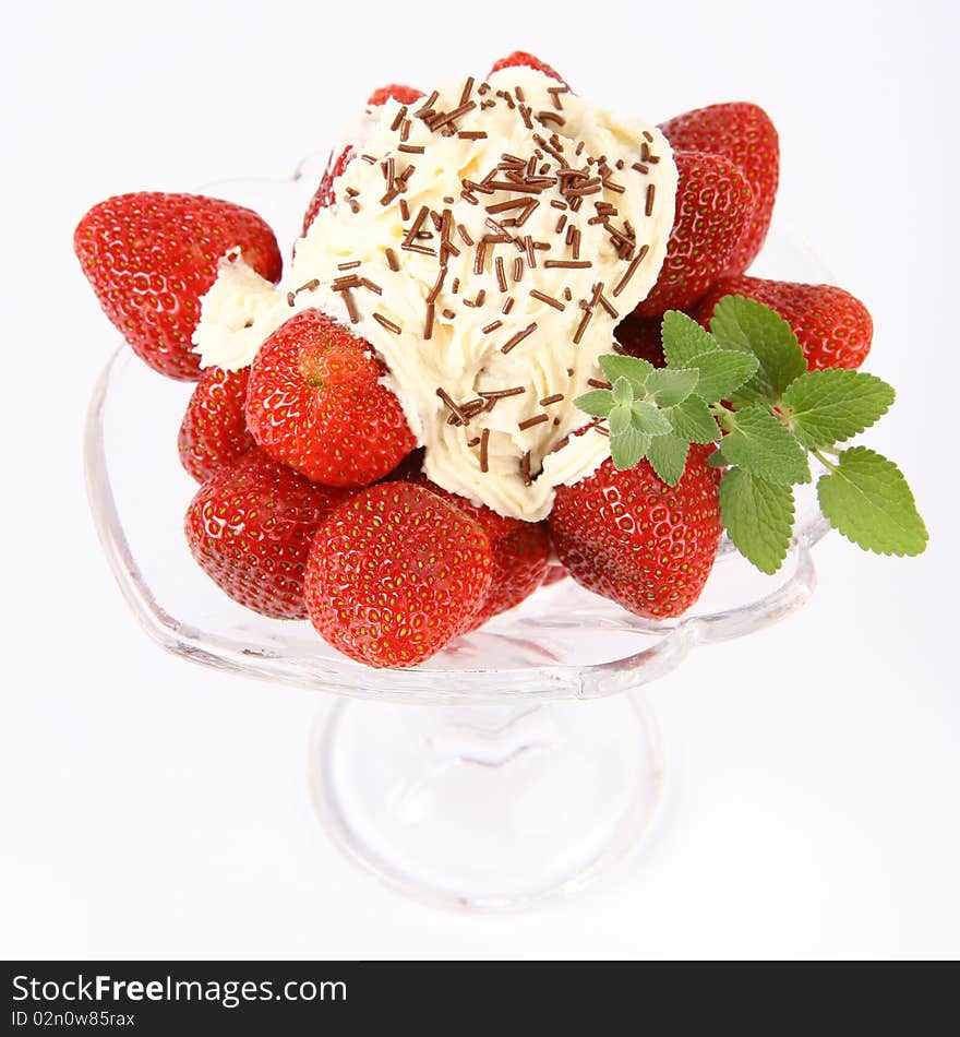 Strawberries in a glass cup with whipped cream, chocolate sprinkles and lemon balm twig. Strawberries in a glass cup with whipped cream, chocolate sprinkles and lemon balm twig