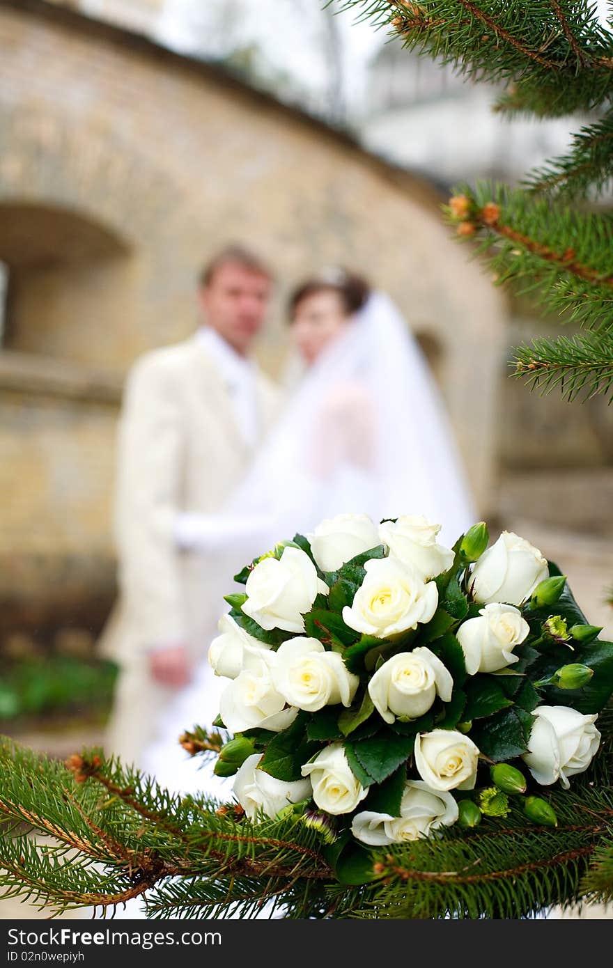 Wedding bouquet in the foreground, the background newlyweds