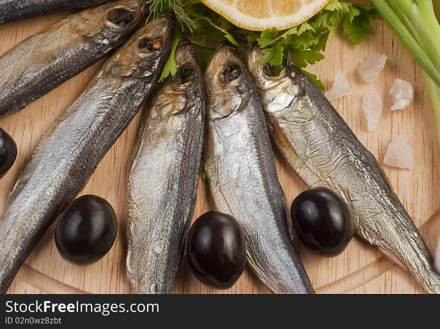 A composition with smoked clupea herring fish (Clupea harengus membras) on wooden plate isolated on white. A composition with smoked clupea herring fish (Clupea harengus membras) on wooden plate isolated on white