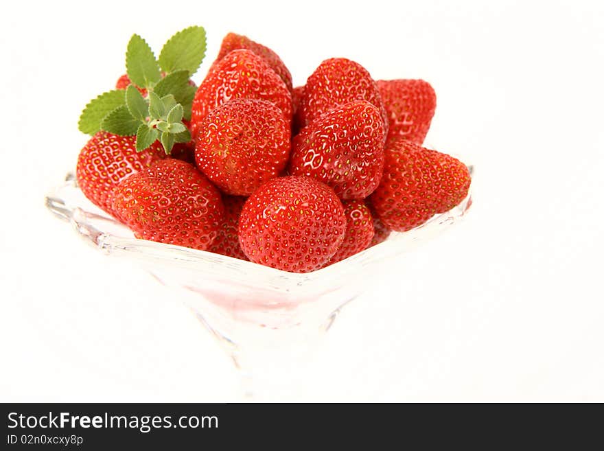 Strawberries in a cup decorated with a lemon balm twig on white background. Strawberries in a cup decorated with a lemon balm twig on white background