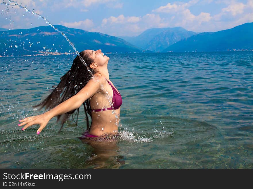 Young, attractive woman, having fun in the water, straying her head back, letting it splash some water. Shot to capture the movement and freeze the action. Young, attractive woman, having fun in the water, straying her head back, letting it splash some water. Shot to capture the movement and freeze the action