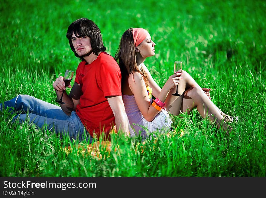 Boy and nice girl with wineglasses on grass