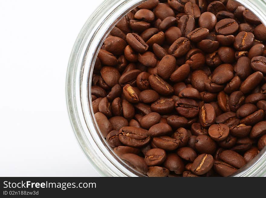 Grains жаренного coffee in a glass jar on a white background. Grains жаренного coffee in a glass jar on a white background