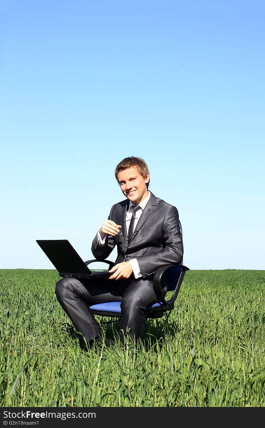 Businessman relaxing on green grassland, under blue sky. Businessman relaxing on green grassland, under blue sky