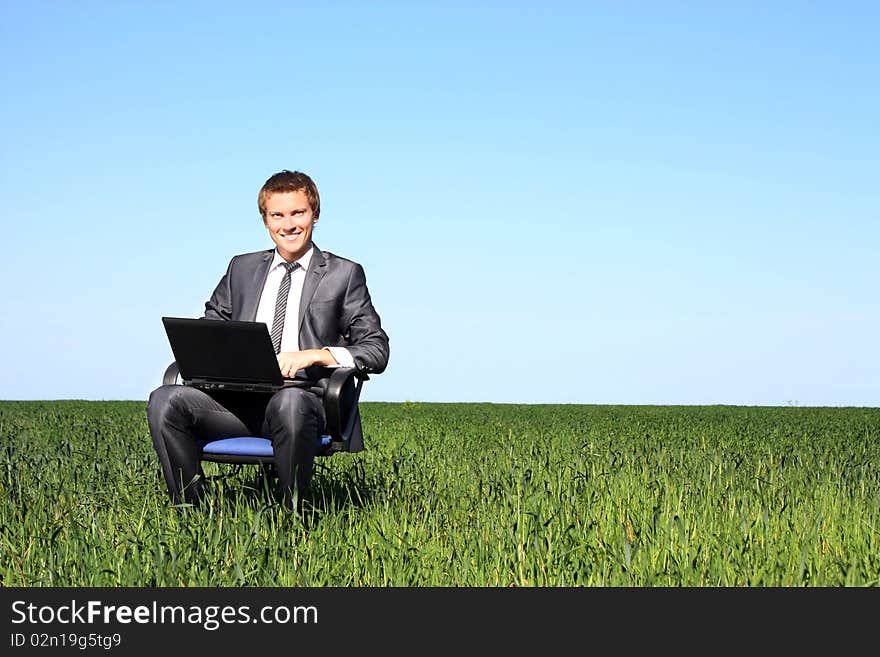 Happy businessman on field, with a laptop