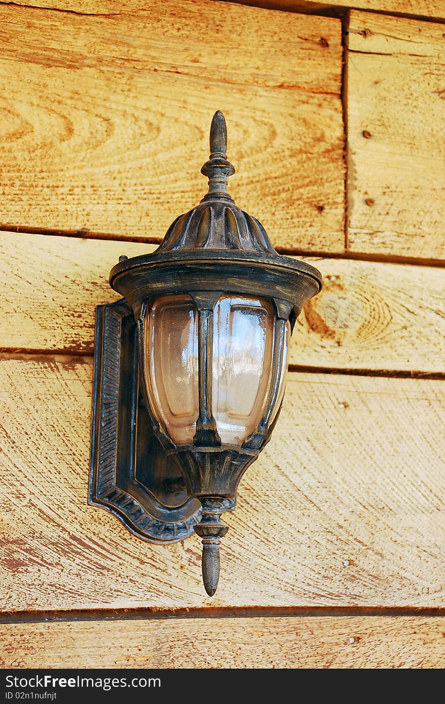 Old fashioned ornamental light on wooden wall. Old fashioned ornamental light on wooden wall