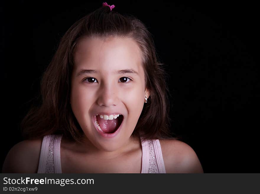 Girl screaming on a black background. Ten years old