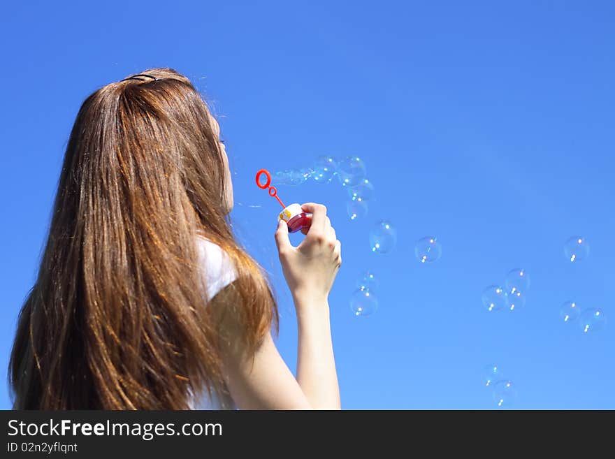 Girl blowing bubbles on a blue background