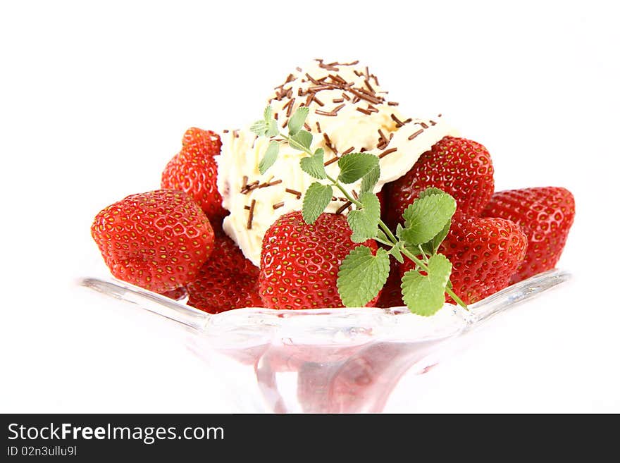 Strawberries in a glass cup with whipped cream, chocolate sprinkles and lemon balm twig. Strawberries in a glass cup with whipped cream, chocolate sprinkles and lemon balm twig